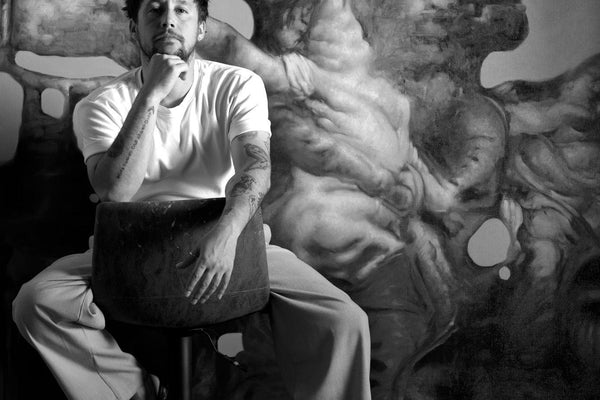 Darian Mederos en su estudio junto a su pintura